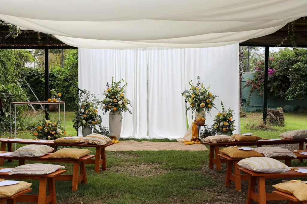 Decoración de boda en Jardin Les Barraques con bancos de madera, flores y fondo blanco en un entorno natural de la Albufera de Valencia.