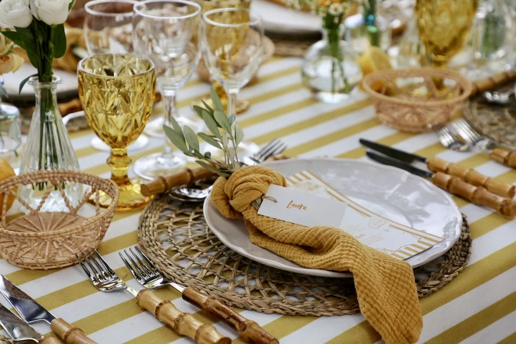 Detalle de mesa de boda en Jardin Les Barraques con vajilla, copas doradas, flores y limones en la Albufera de Valencia.